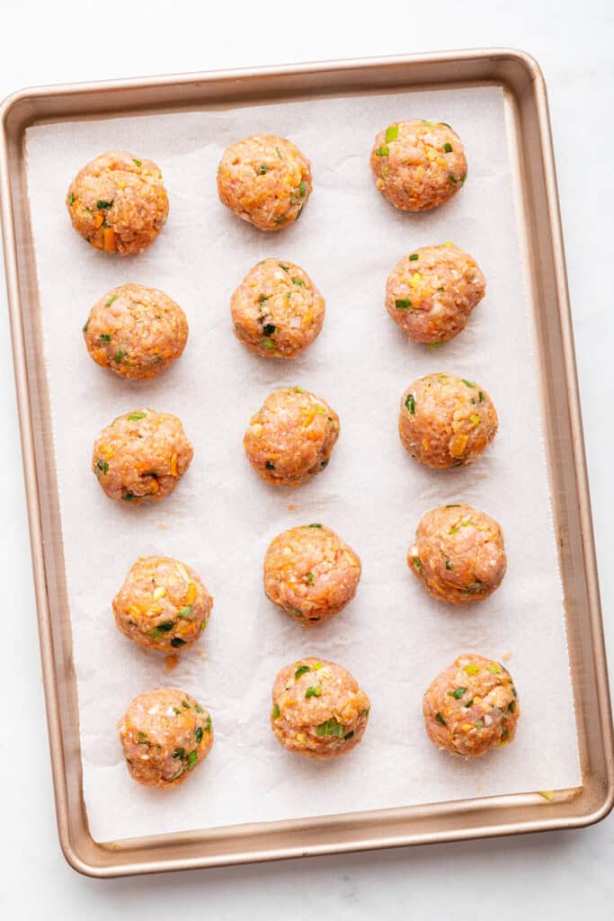 Overhead view of Asian turkey meatballs on baking sheet before baking