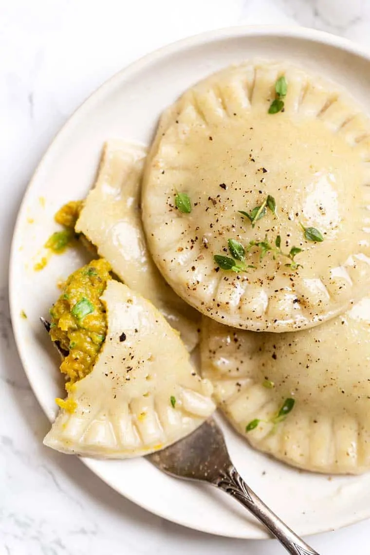 Three gluten free ravioli with butternut-spinach filling on a serving plate.