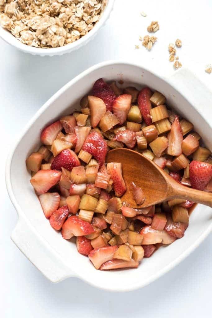 Roasted strawberry and rhubarb mixture in baking dish with wooden spoon