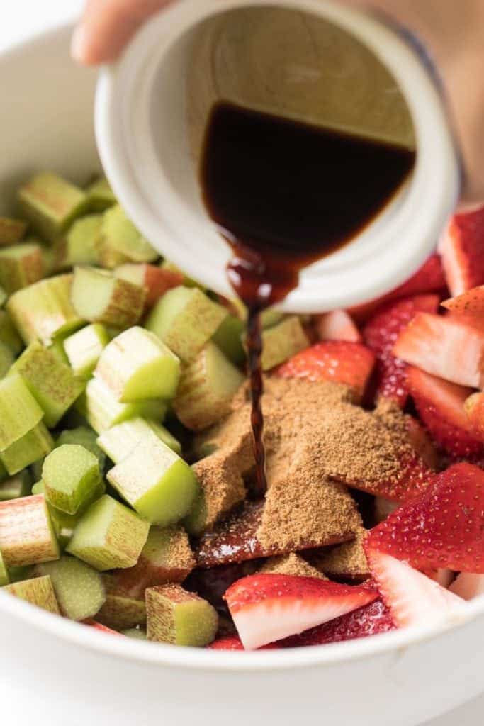 Pouring balsamic vinegar into bowl of strawberries and rhubarb