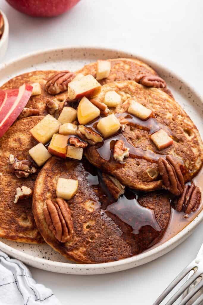 Plate of oatmeal pancakes with syrup, pecans, and apples