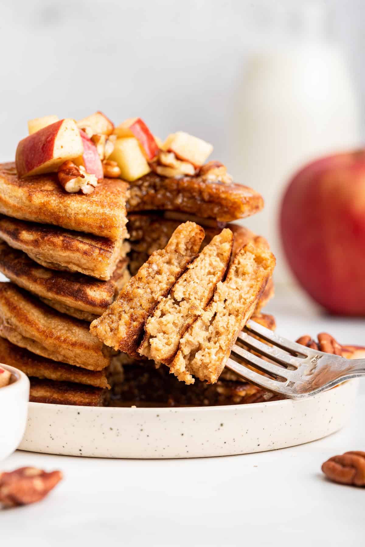 Fork digging into stack of fluffy oatmeal pancakes