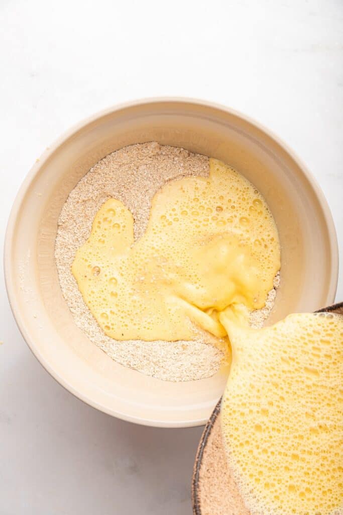 Pouring liquid ingredients into dry ingredients for oatmeal pancakes