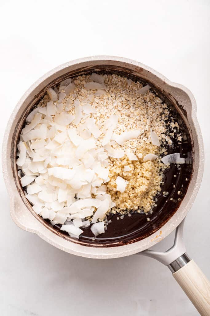 Overhead view of coconut, quinoa, and oats added to saucepan