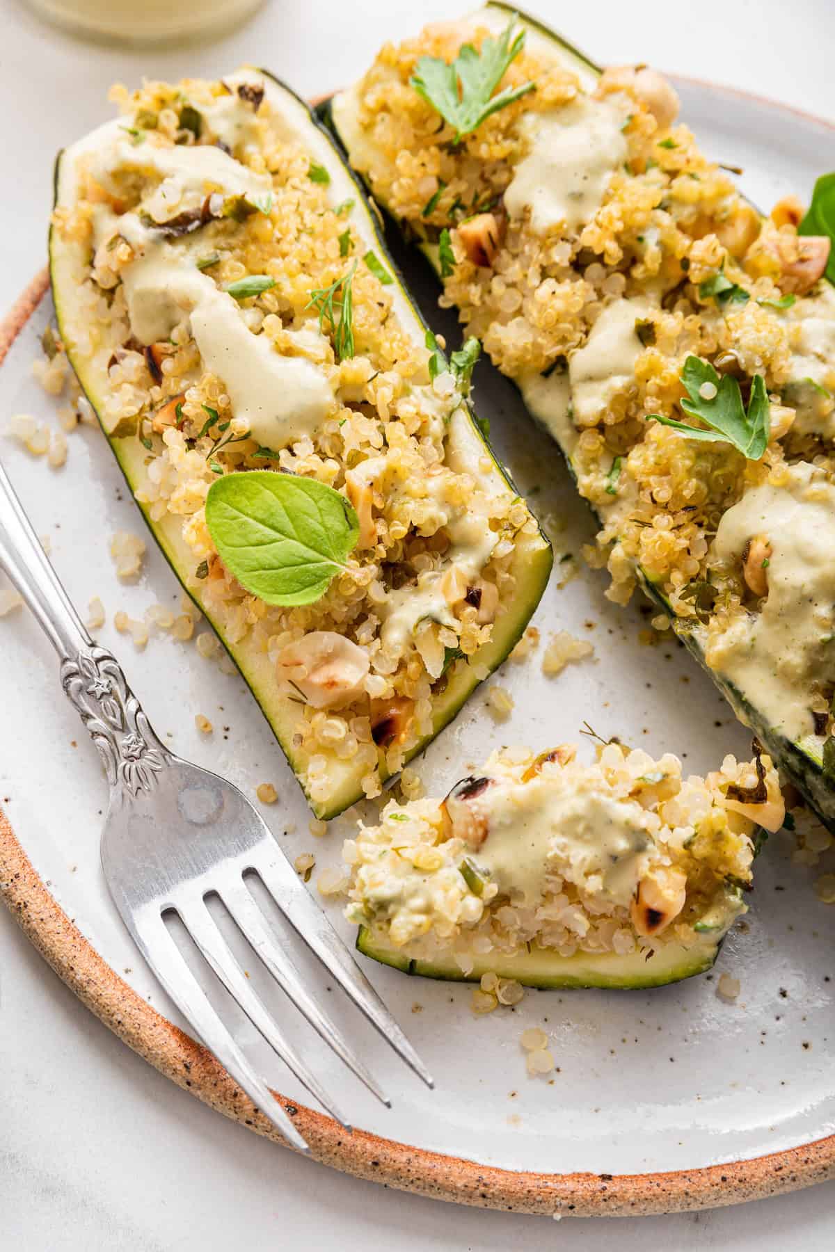 Quinoa stuffed zucchini boats on plate with bite from end
