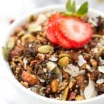 Bowl of grain-free coconut granola with sliced strawberry