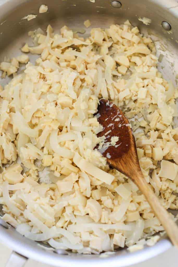 Overhead view of hearts of palm and onion cooking in skillet