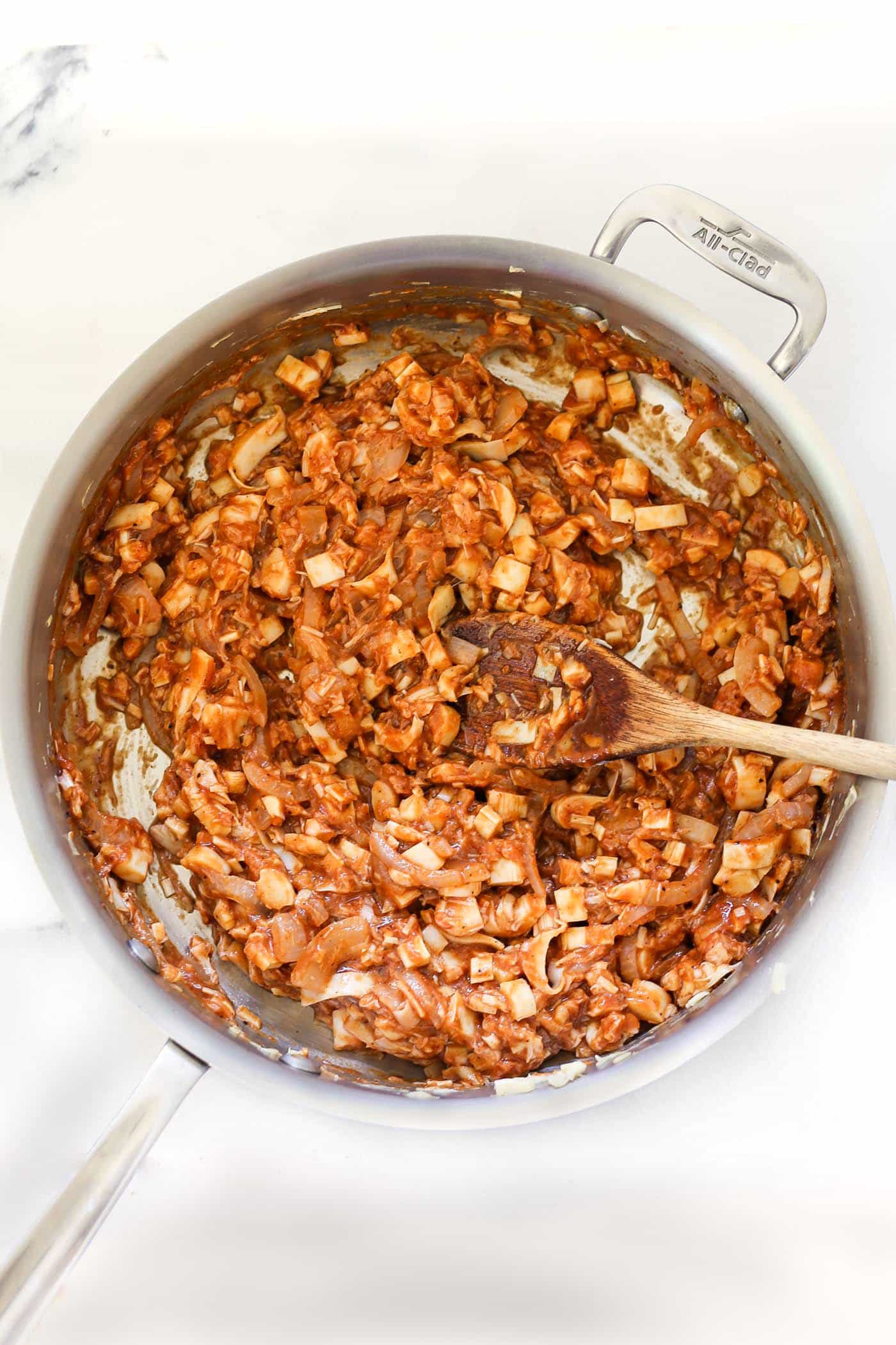 Overhead view of BBQ vegan pulled pork in skillet with wooden spoon