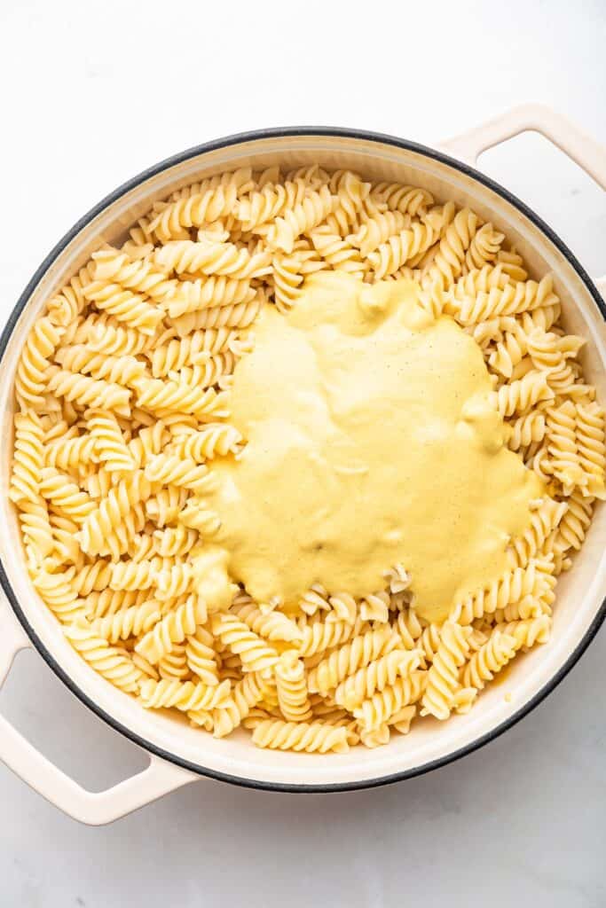 Cashew cheese sauce added to pasta in baking dish