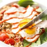 Slicing into the egg yolk in my savory breakfast quinoa bowl.