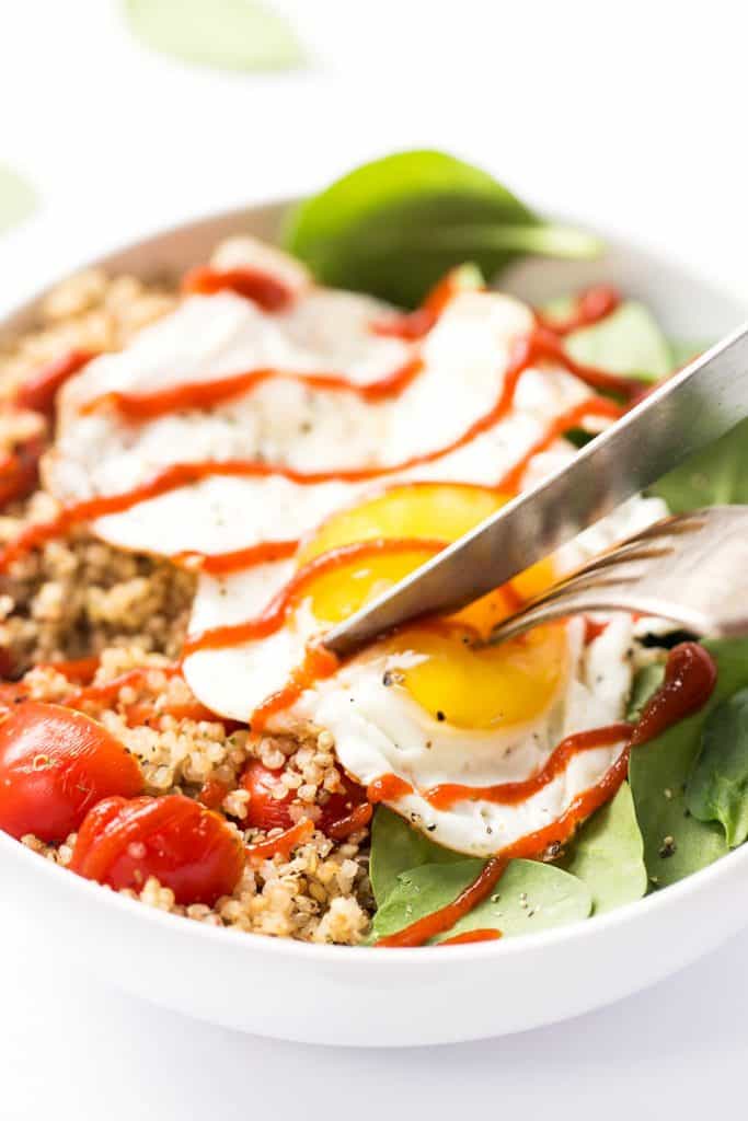 Slicing into the egg yolk in my savory breakfast quinoa bowl.