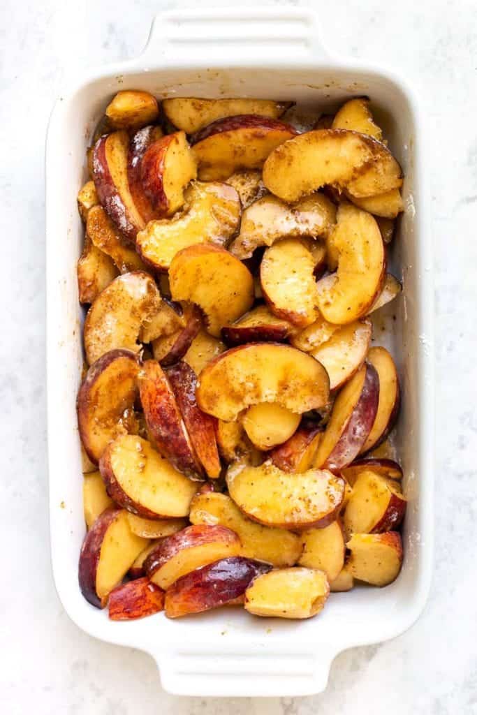 A baking dish with sliced peaches.