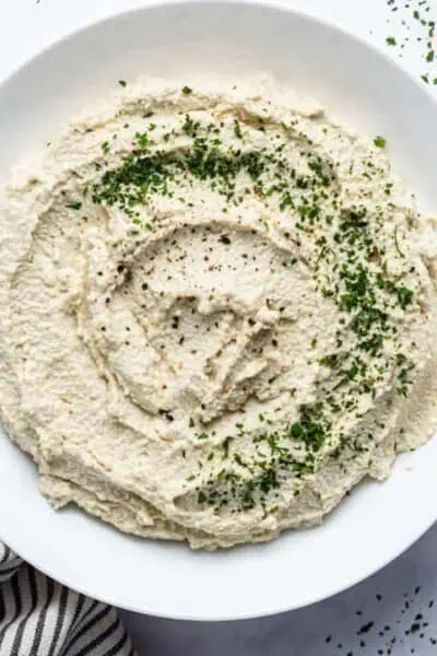 close up on vegan tofu ricotta in a white bowl with herbs for garnish