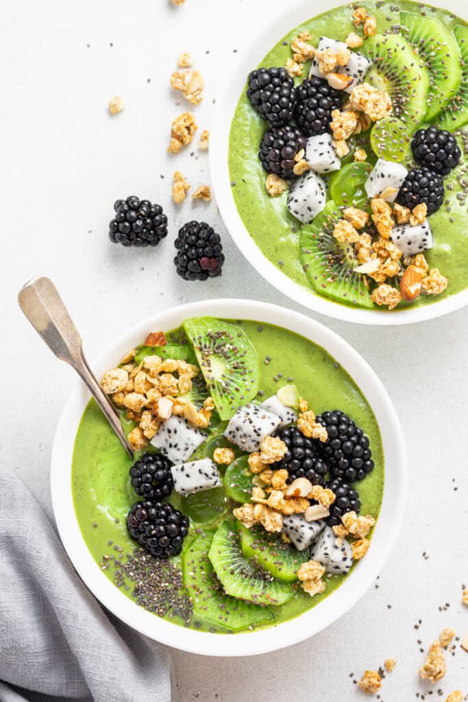 two bowls of green smoothie with fresh fruit