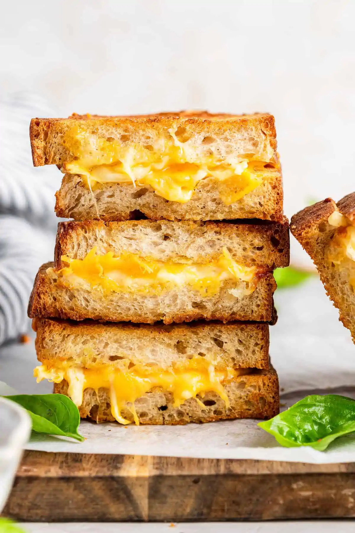 Vegan grilled cheese sandwiches stacked on top of one another, showing the melty cheese inside.