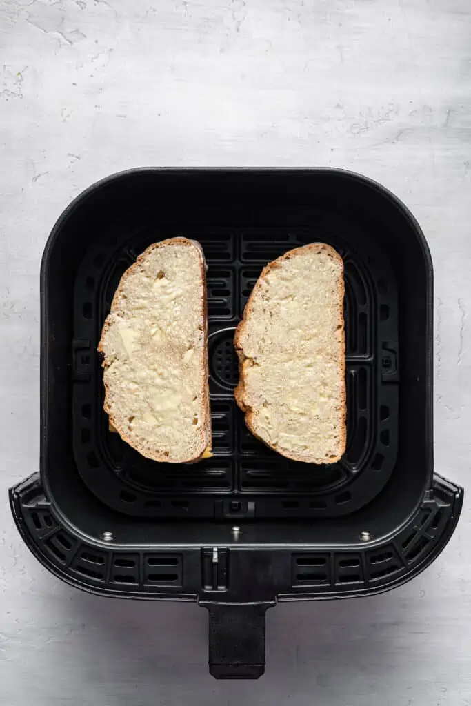 Two slices of buttered bread inside the air fryer.