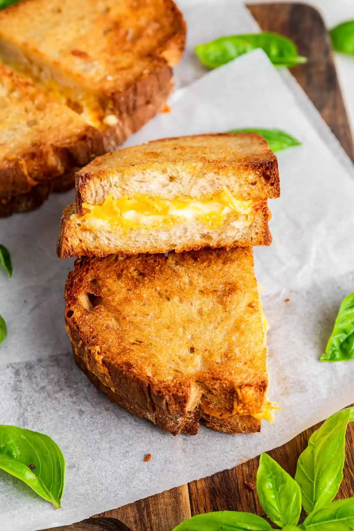 Two halves of a vegan grilled cheese sandwich stacked on top of one another, showing the melty cheese inside.