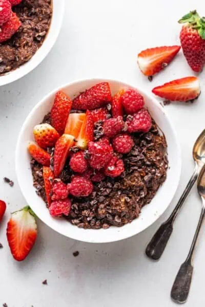 Top view of chocolate protein oatmeal in a white bowl, topped with fresh mixed berries.