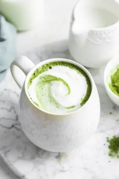 A classic matcha latte topped with steamed milk in a white mug.