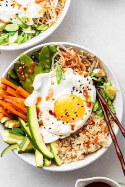 Vegetarian Korean bibimbap topped with a fried egg with chopsticks resting on the bowl.