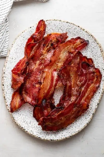 Crispy air fryer bacon strips on a white plate.