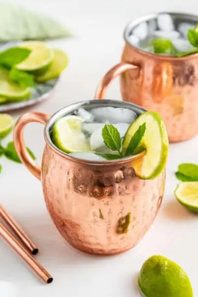 Two Mexican mules in copper mugs with ice, garnished with mint leaves and limes.