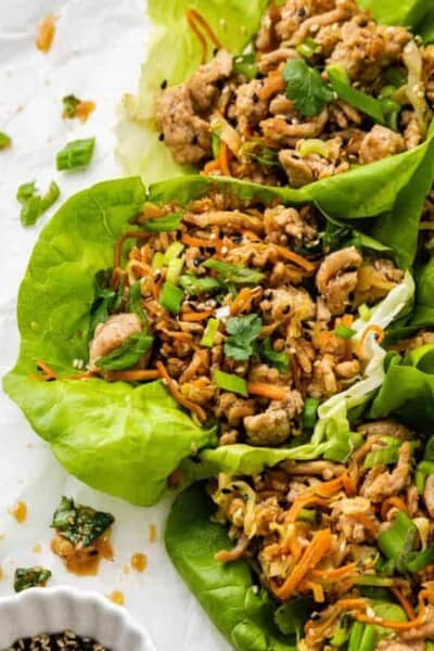 A tray of chicken lettuce wraps surrounded by sliced scallions