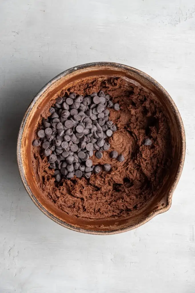 A mixing bowl with espresso cookie dough, with chocolate chips on top.
