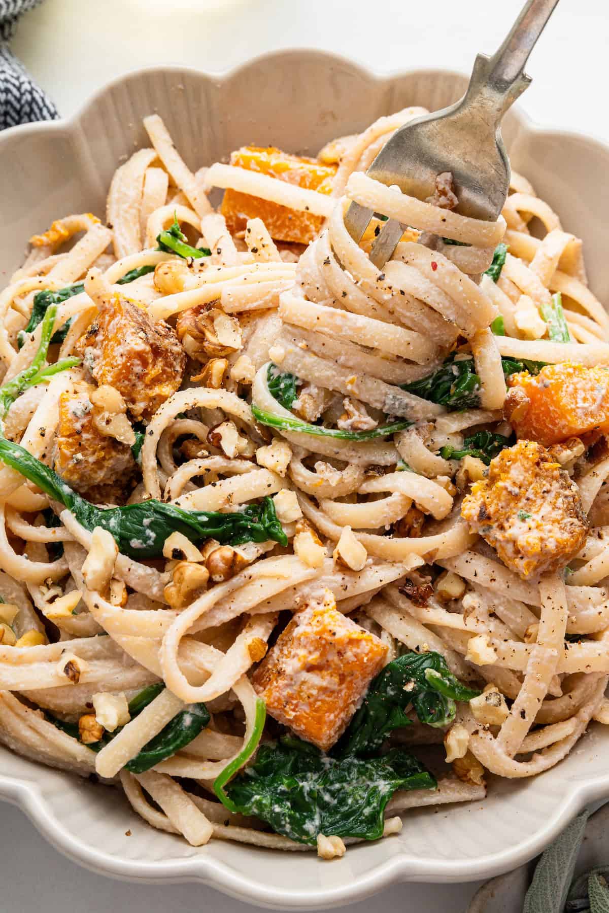 Twisting walnut pasta around fork in bowl