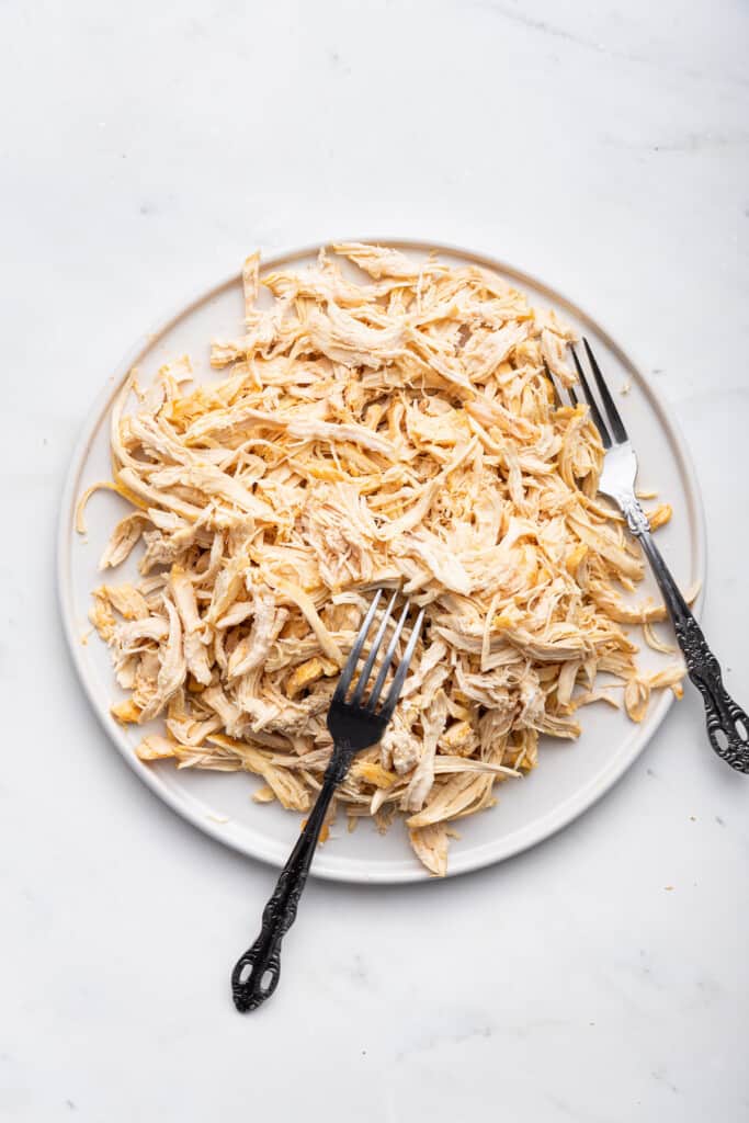 Overhead view of Instant Pot shredded chicken on plate with 2 forks