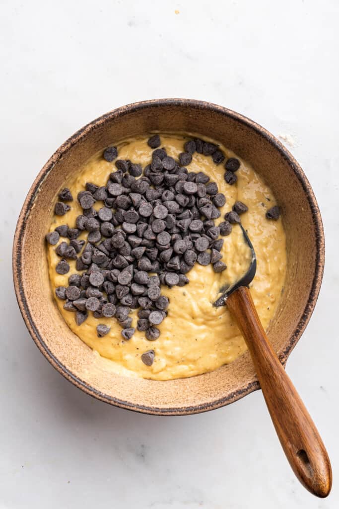 Overhead view of chocolate chips added to bowl of protein banana bread batter