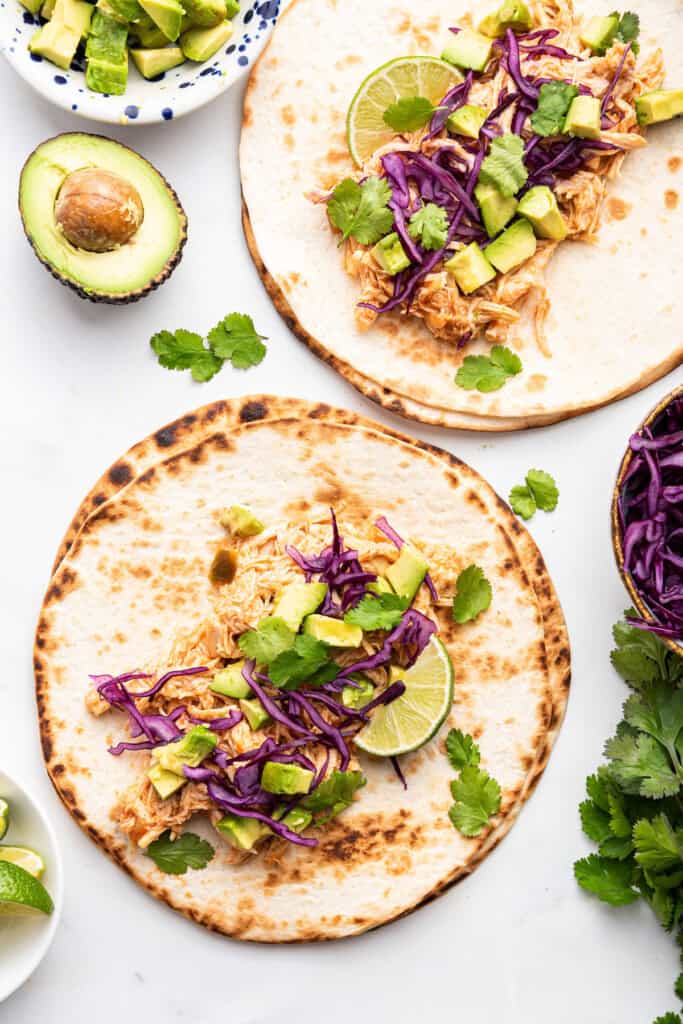 Two tortillas topped with Instant Pot shredded chicken for tacos