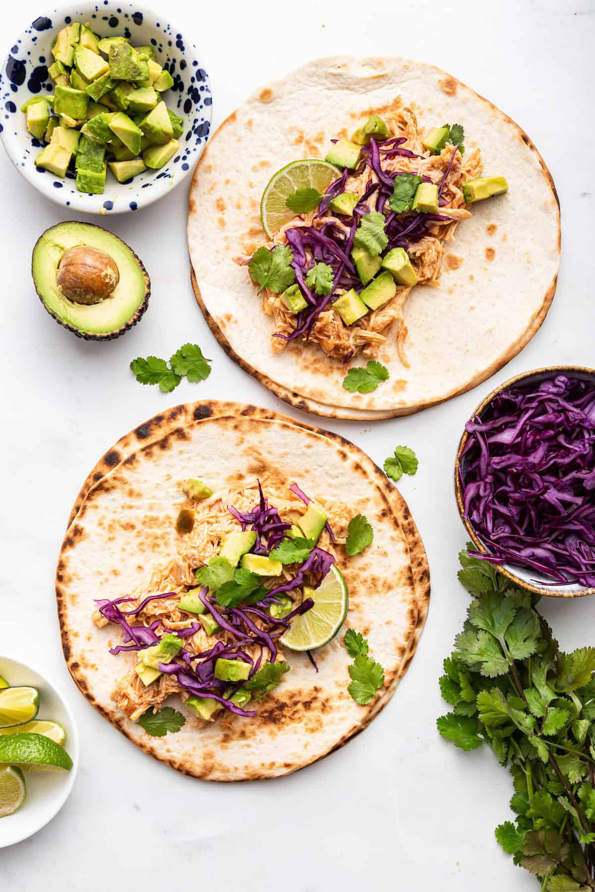 Overhead view of Instant Pot shredded chicken taco filling on 2 tortillas with toppings