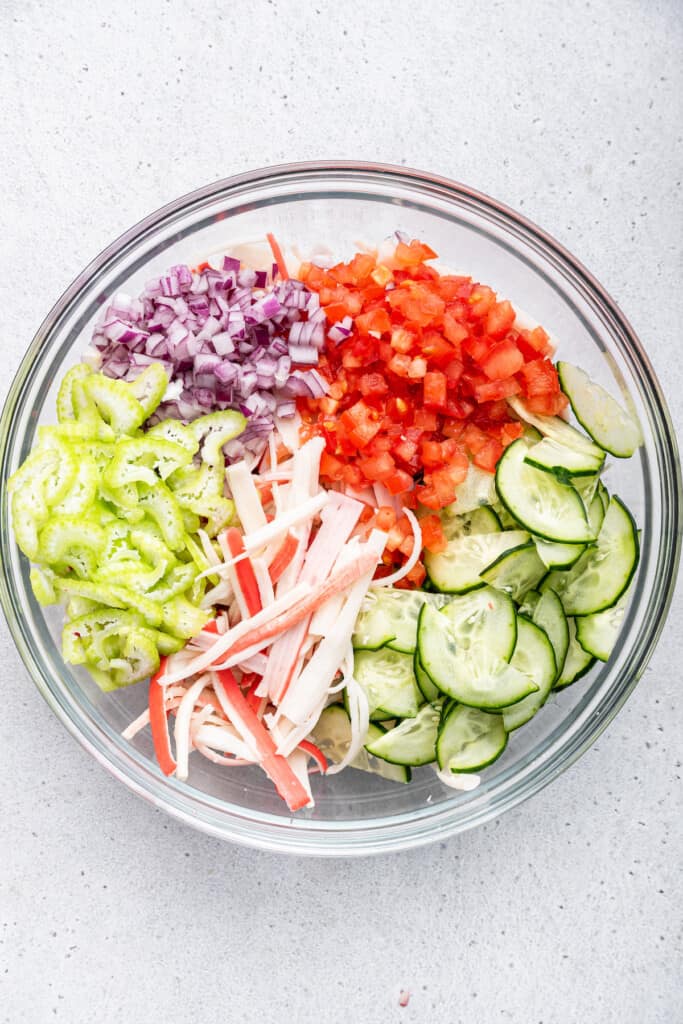 Overhead view of vegetables and shredded imitation crab in mixing bowl