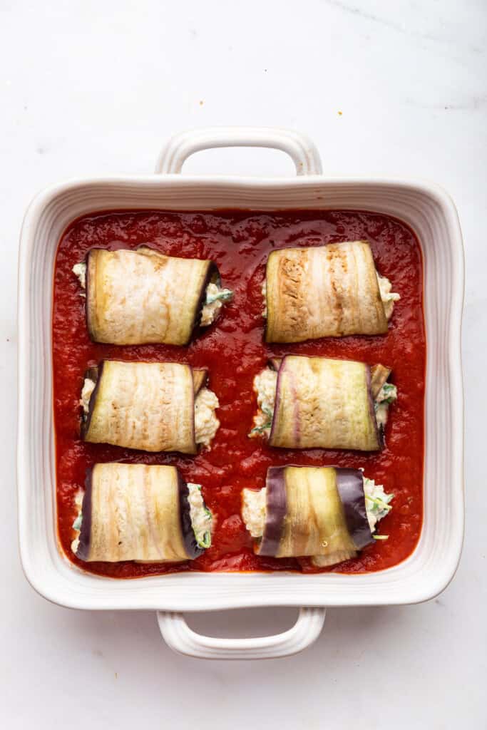 Eggplant rolls in baking dish with marinara