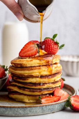 Pouring maple syrup onto stack of Greek yogurt pancakes