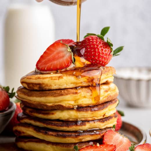 Pouring maple syrup onto stack of Greek yogurt pancakes