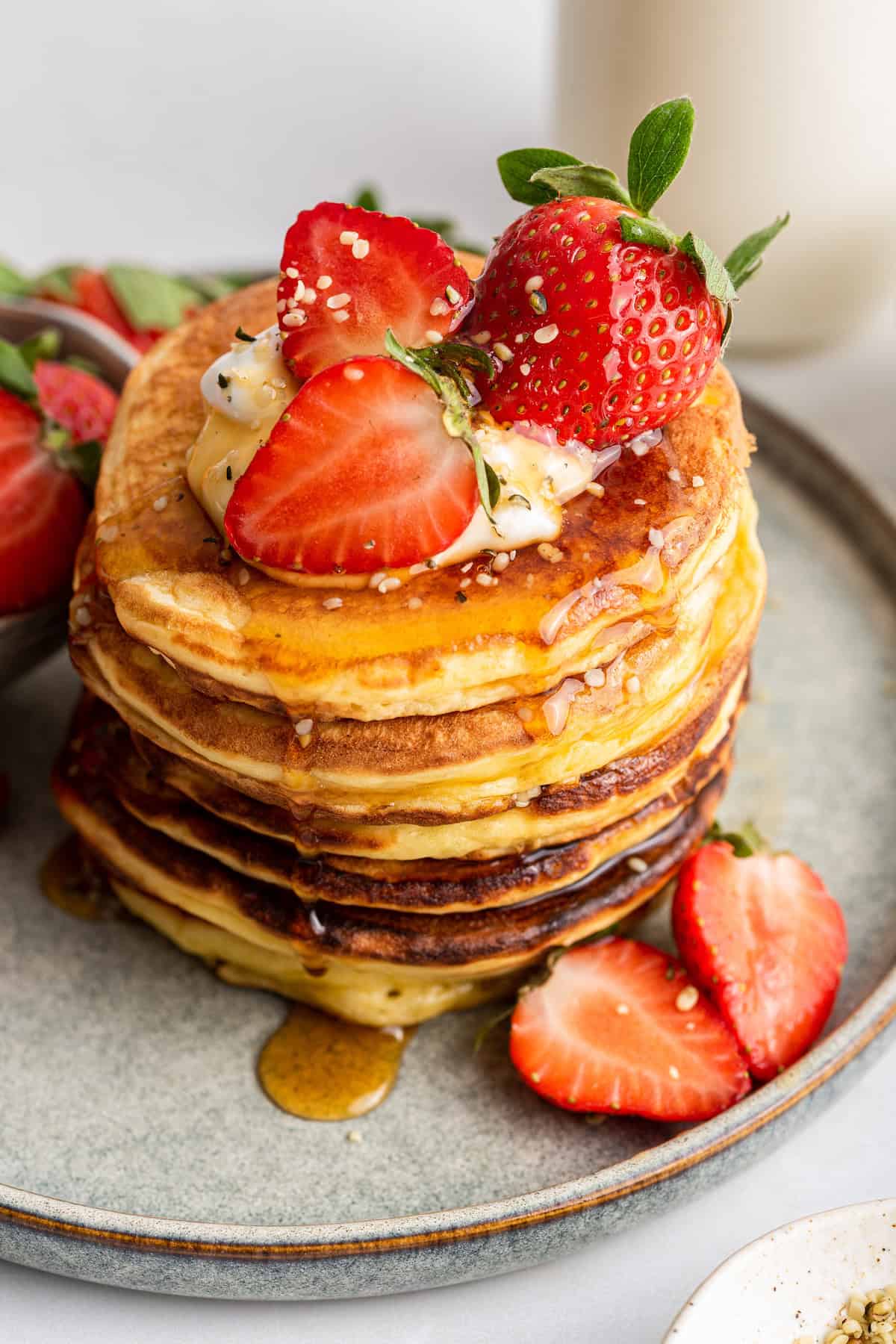 Stack of fluffy Greek yogurt pancakes on plate with yogurt and strawberries