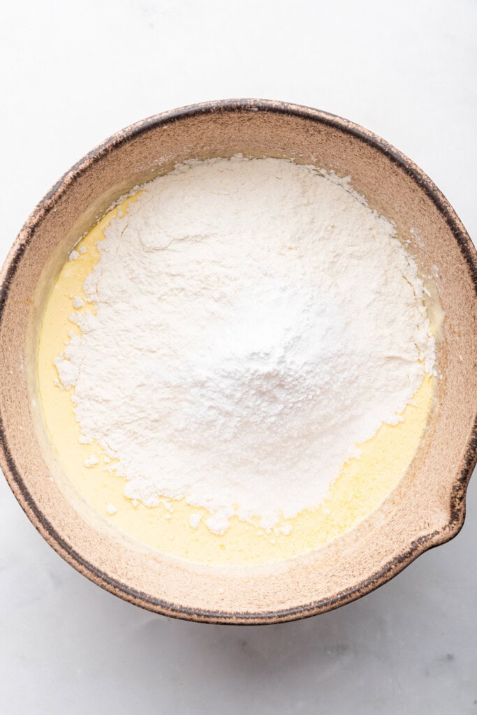 Overhead view of dry ingredients added to wet ingredients in bowl