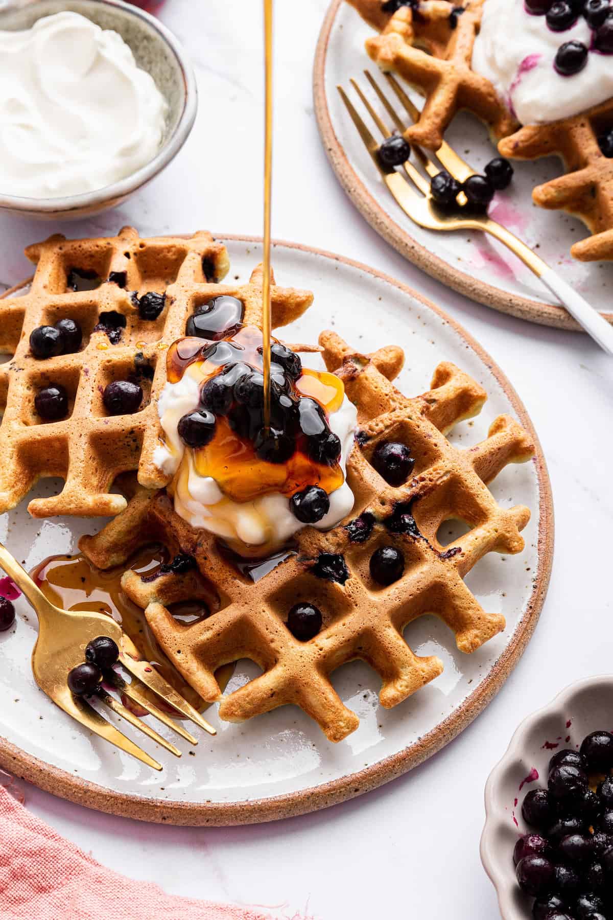 Drizzling maple syrup onto blueberry waffles