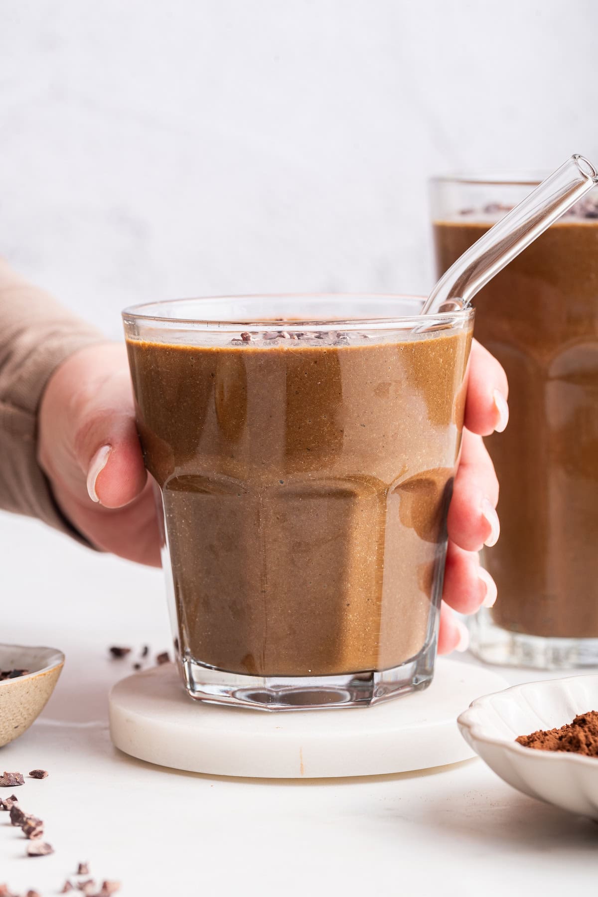 Hand holding chocolate peanut butter smoothie in glass