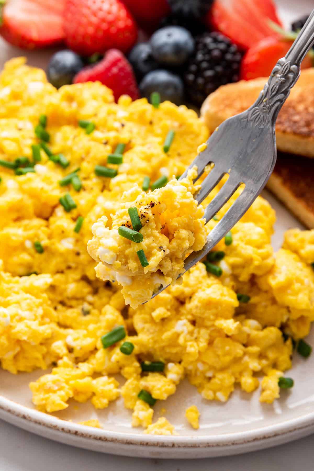 Forkful of fluffy cottage cheese scrambled eggs held over plate