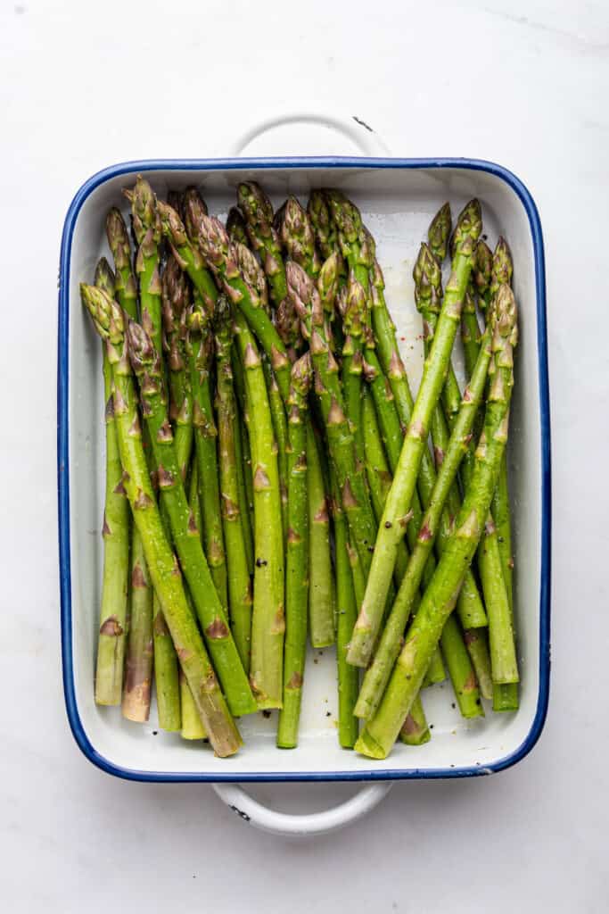 Overhead view of seasoned asparagus in baking dish