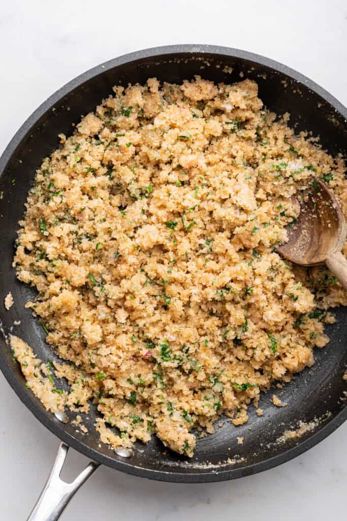 Overhead view of breadcrumb mixture for stuffed artichokes in skillet