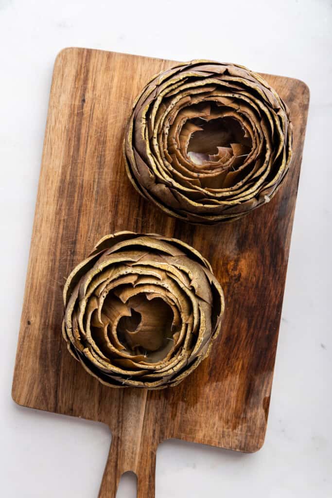 Overhead view of steamed and prepared artichokes on cutting board