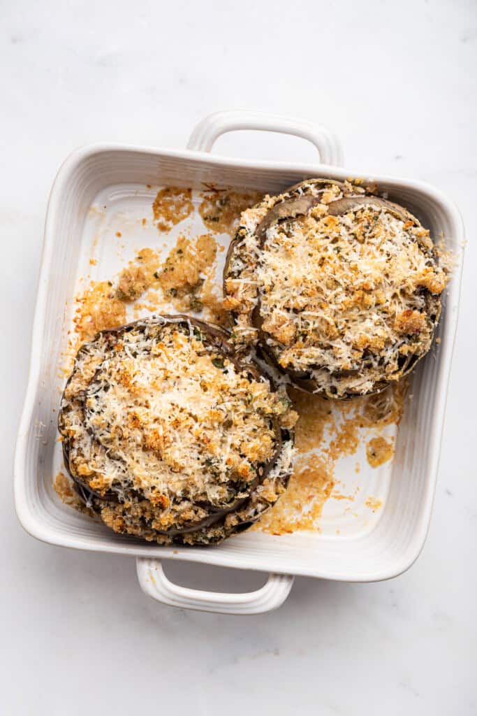 Overhead view of 2 stuffed artichokes in baking dish