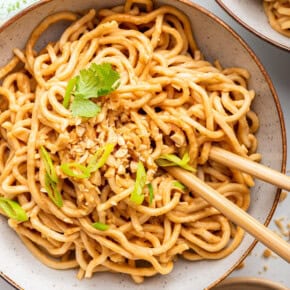 Overhead view of peanut noodles in bowl with chopsticks