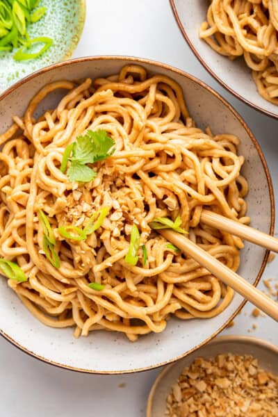 Overhead view of peanut noodles in bowl with chopsticks