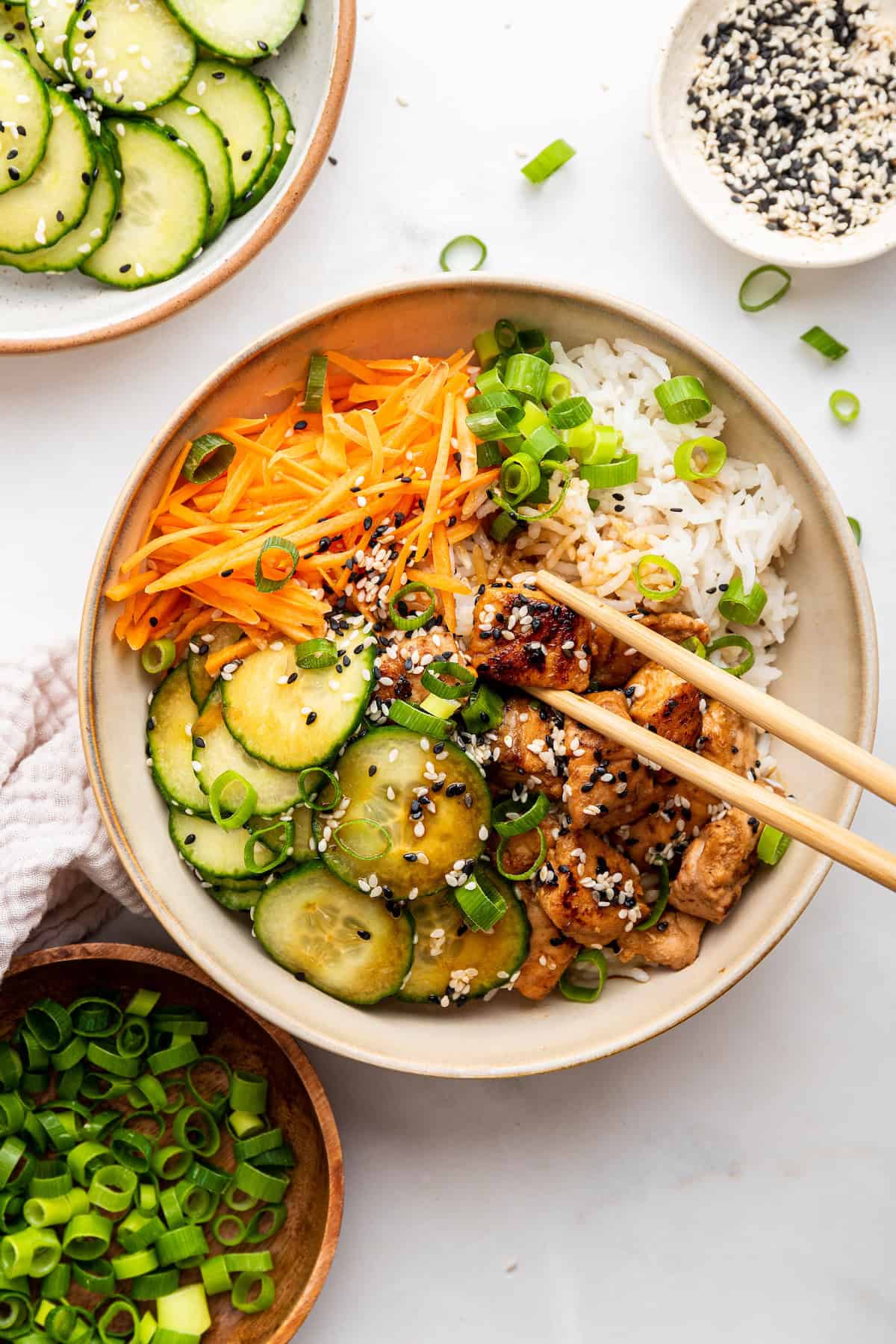 Overhead view of salmon bowl with chopsticks lifting piece of baked salmon