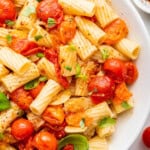 Overhead view of easy cherry tomato pasta in bowl with fresh basil leaves